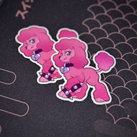 two pink poodle stickers on a black surface